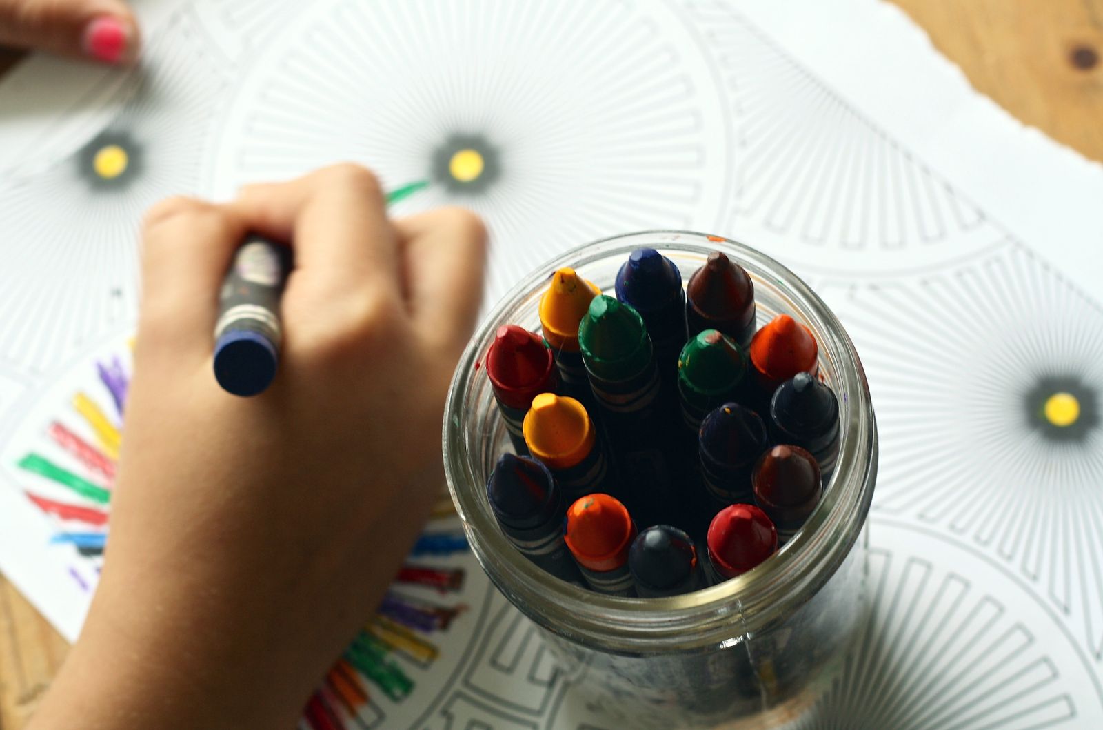 Child coloring with a jar of crayons, an educational Easter basket activity